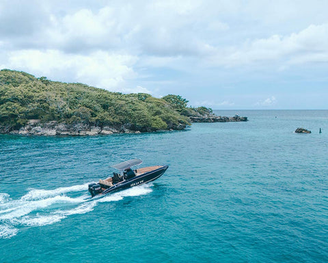 Speedboat on a clear blue sea with a rocky island in the Rosario Islands