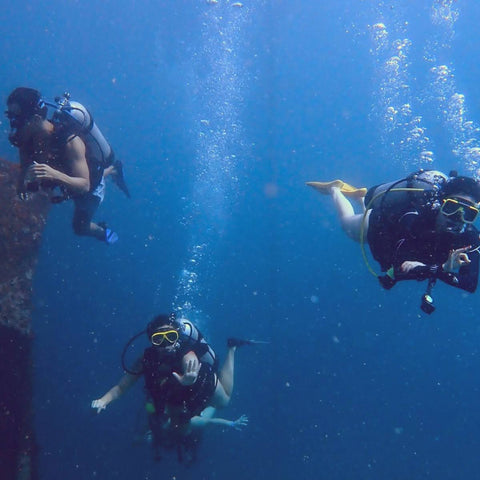 Three scuba divers underwater in a clear blue sea in Baru