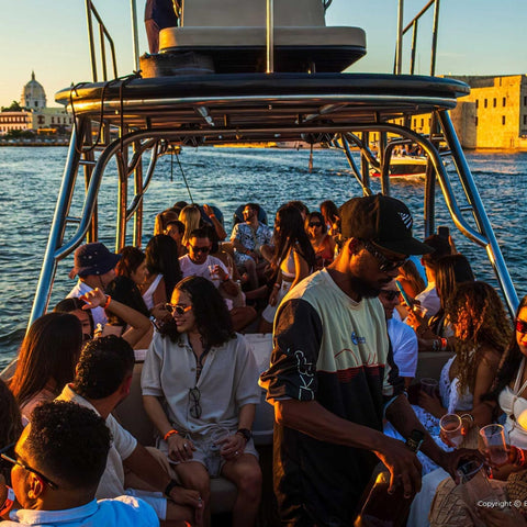 Group of people on a boat at sunset with cityscape in the background