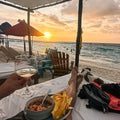 Person enjoying a sunset at the beach with food and a glass of wine in playa blanca